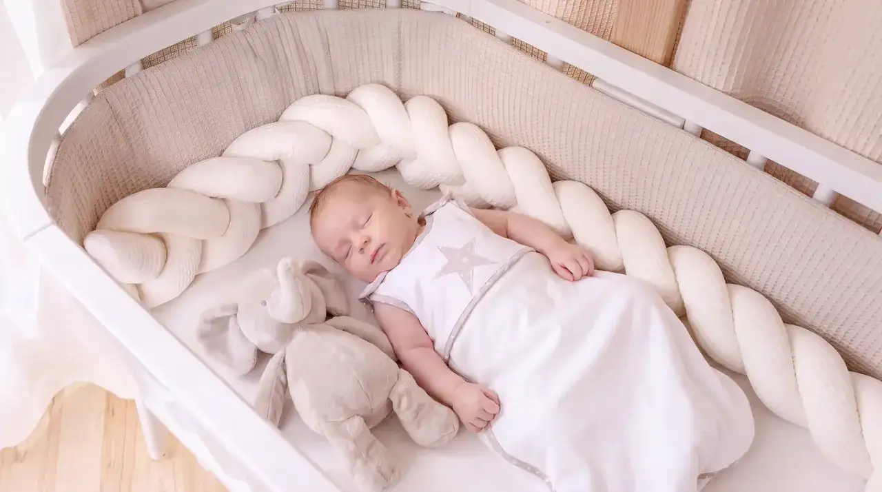 Ein Baby schl&auml;ft friedlich in seinem Bettchen, umgeben von einem weichen Nestchen. Vielleicht ist es eine Phase der schlafregression baby, aber gerade ist alles ruhig.