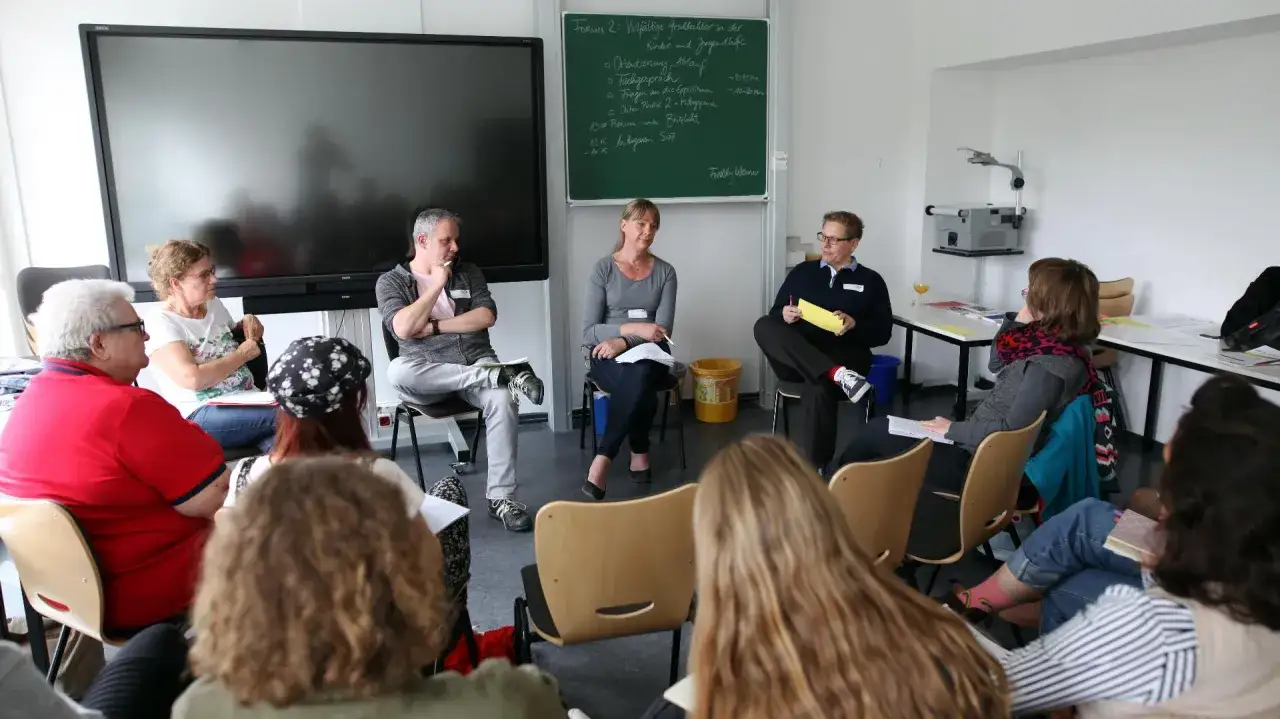 Diskussion über die Unterstützung von transgender Kindern und Jugendlichen in der Kinder- und Jugendhilfe. Mehrere Personen sitzen im Kreis.