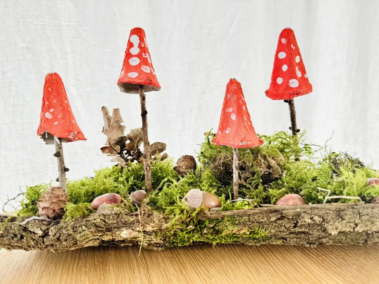 Kleine Fliegenpilze aus Eierkartons, ein sch&ouml;nes Beispiel f&uuml;r Herbst basteln Kita, stehen auf Moos und Holz.