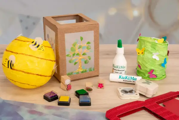 Bastelmaterialien für eine Laterne: Bienen-Laterne, Baum-Laterne, Kleber, Stempel & Schmetterlingsstanzer. Eine Vorlage zum Laterne basteln.