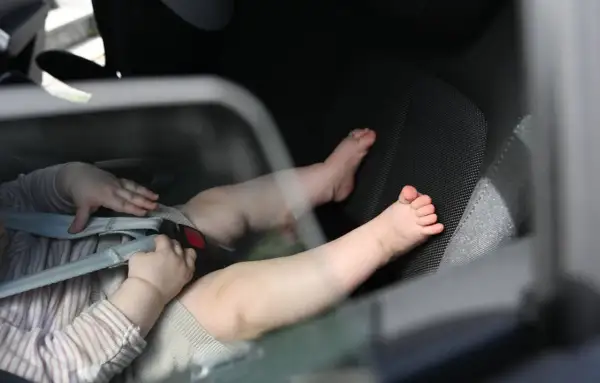 Babyfüße im Kindersitz. Ein trauriges Bild, das an das "forgotten baby syndrome" erinnert, wenn Kinder versehentlich im Auto zurückgelassen werden.