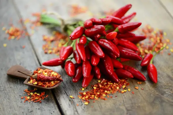 Ein Bund scharfer Chilis und Chiliflocken auf Holz. Perfekt, um jedes Gericht zu würzen und den Geschmack zu stillen.