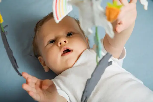 Ein neugieriges Baby, 15 Wochen alt, streckt seine Hand nach einem Spielzeug aus.